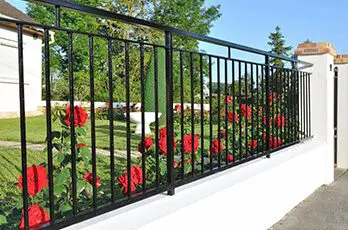 A black fence with red flowers on it