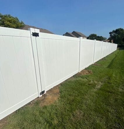White vinyl fence along grassy lawn.